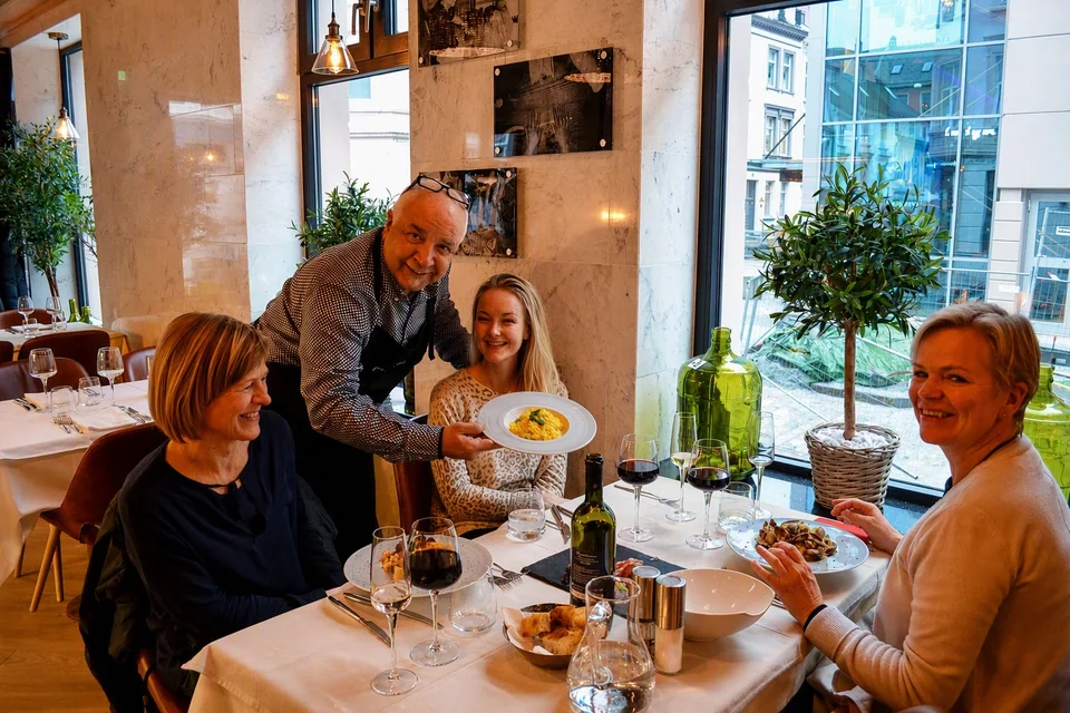 En vert serverer gjester ved et vindusbord hos Amici Miei