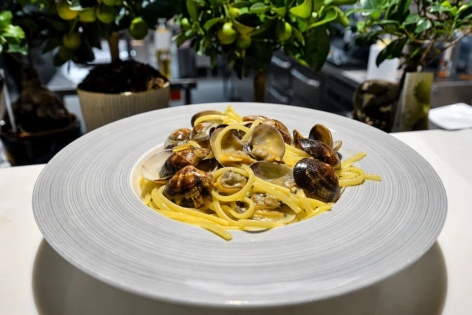 Pasta med skjell på en hvit tallerken ved restaurantens vindu